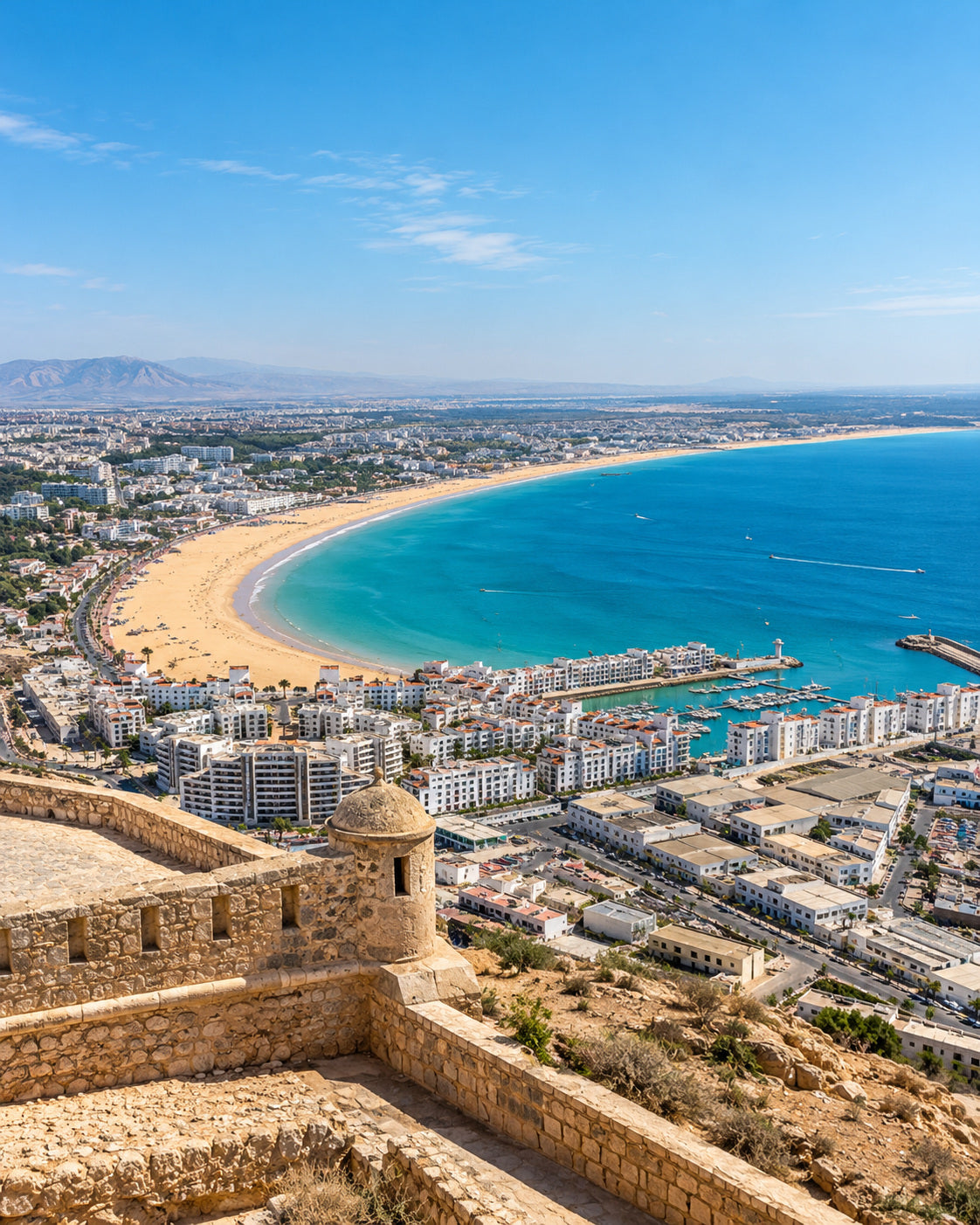 Agadir: playa dorada y Atlántico azul desde Agadir Oufella con edificios blancos de la ciudad
