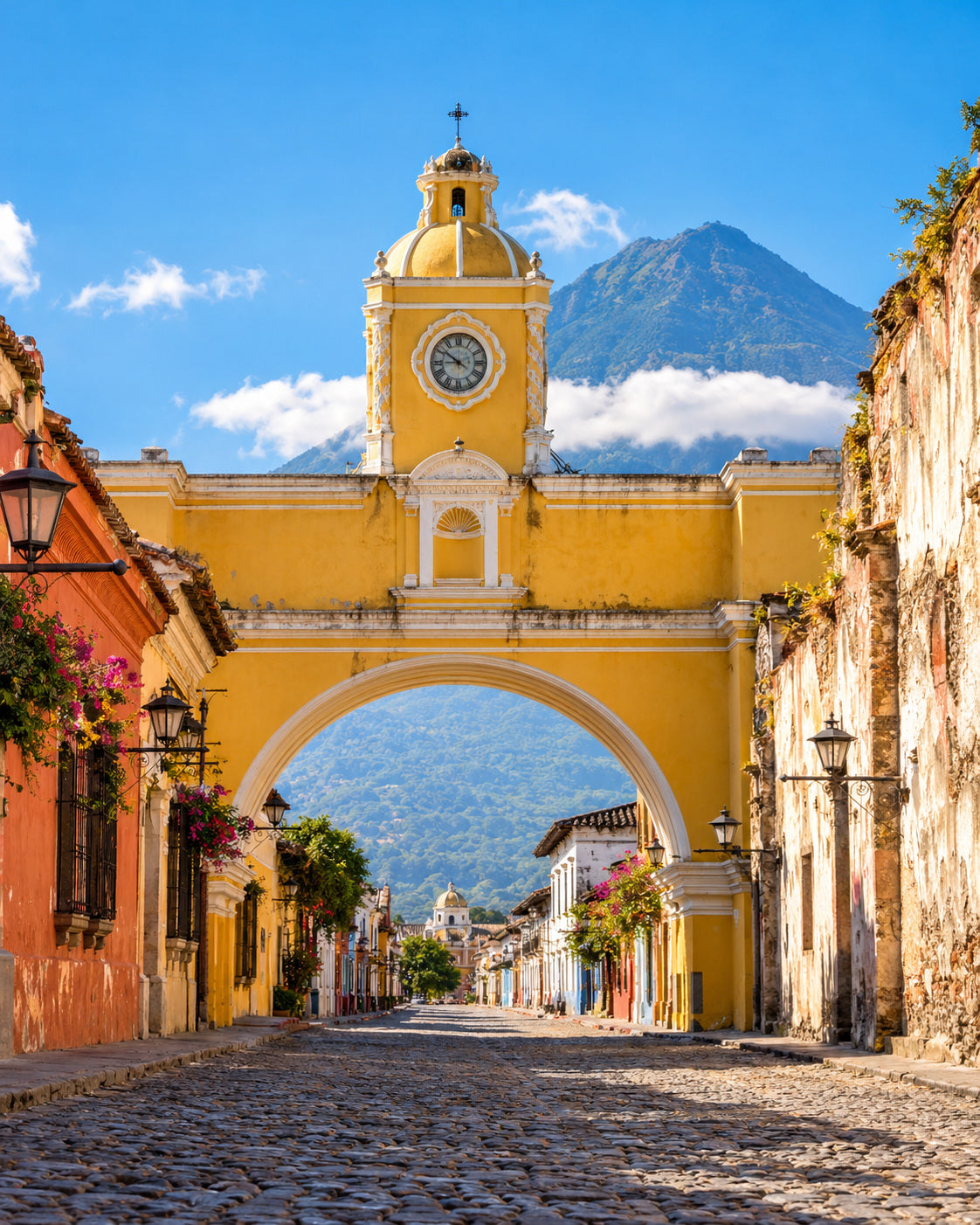 Antigua Guatemala: żółty łuk Santa Catalina z wulkanem Agua w oddali, brukowaną ulicą i kolorowymi fasadami