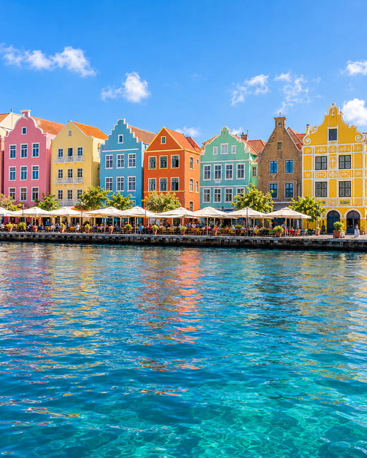 Curaçao: bunte Giebelfassaden der Handelskade in Willemstad mit Spiegelung im blauen Hafenwasser