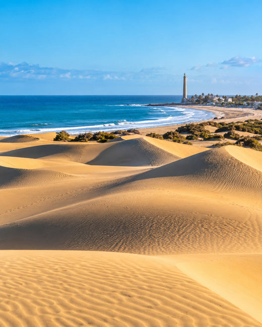 Gran Canaria: goldene Dünen von Maspalomas am blauen Atlantik mit einem Leuchtturm in der Ferne