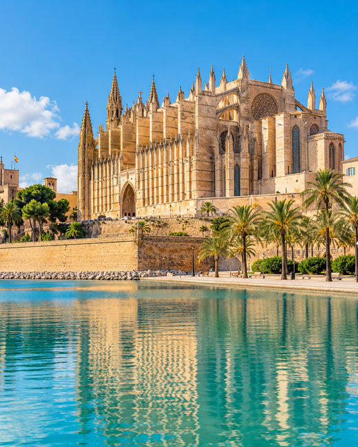 Mallorca: goldene Steinfassade der Kathedrale von Palma mit Wasserbecken im Parc de la Mar und Palmen