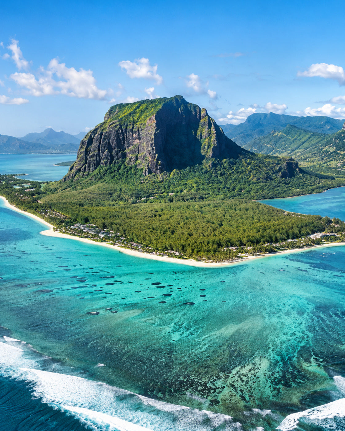Mauritius: le Morne Brabant mountain above a bright turquoise lagoon and coral reef, aerial view in clear natural sunshine