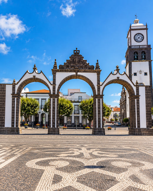 Ponta Delgada: drei schwarz-weiße Bögen der Portas da Cidade mit gemustertem Pflaster und blauem Himmel