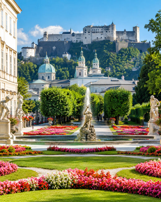 Salzburg: Blumen und Statuen im Mirabellgarten vor der Festung Hohensalzburg im Sonnenschein