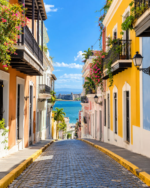 San Juan: bunte Kolonialhäuser in Alt-San-Juan an einer Kopfsteinpflastergasse mit Meerblick in der Ferne