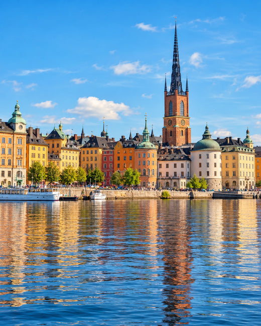 Stockholm: bunte Uferfassaden von Gamla Stan und die Spitze der Riddarholmskyrkan mit Spiegelungen im Wasser